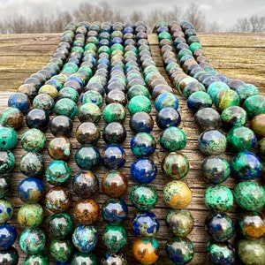 Azurite stone beads strands laid on bright wood surface in outdoor and pictured under natural day light.