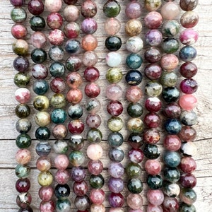 Tourmaline stone beads strands hanging over a bright wood board at outdoors and pictured under natural day light