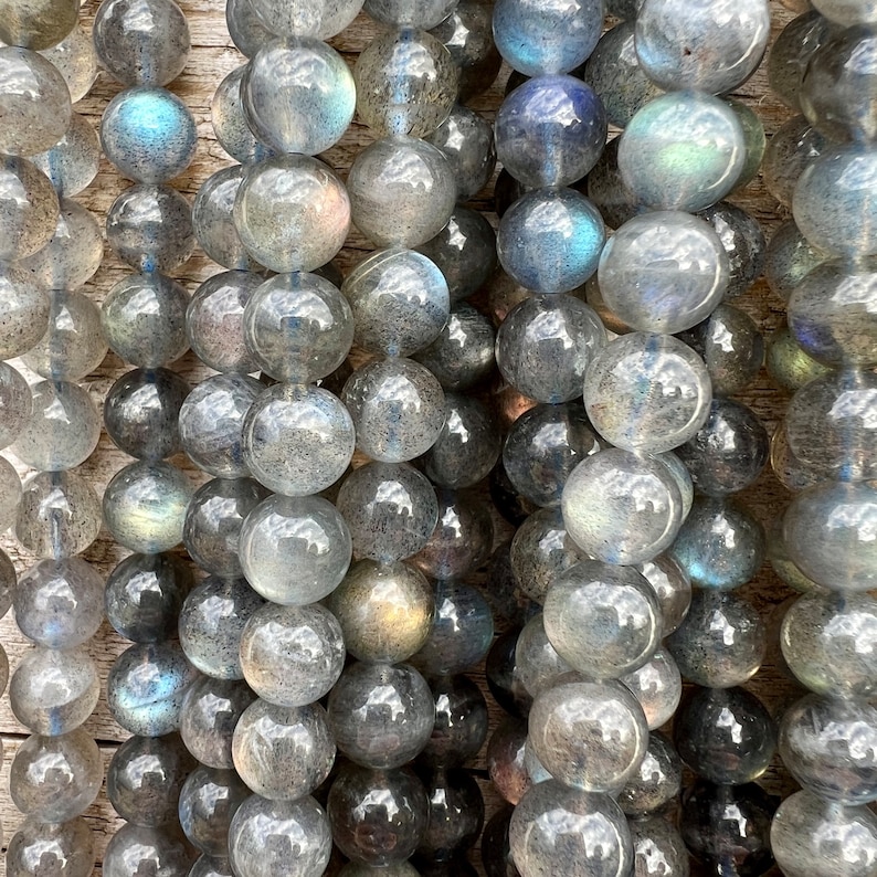 Labradorite stone beads strands laid on a bright wood board in outdoors under natural light.