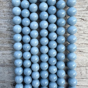 Op de afbeelding: Een streng lichtblauwe ronde edelsteen kralen. De kralen zijn glad en gepolijst.