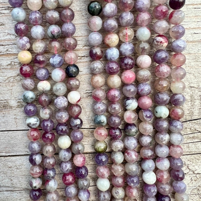 Cherry Tourmaline gemstone beads strands laid on a bright wood board in outdoors under natural daylight. this picture is taken from a further distance