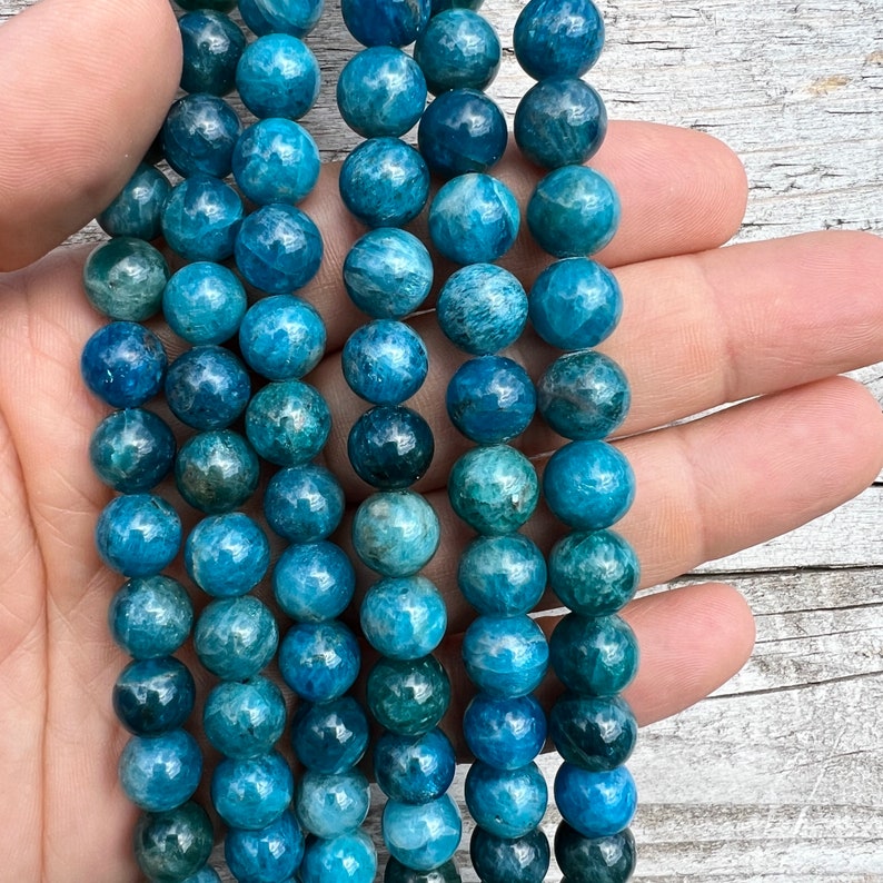 10mm Apatite stone beads strands held in hand on white background