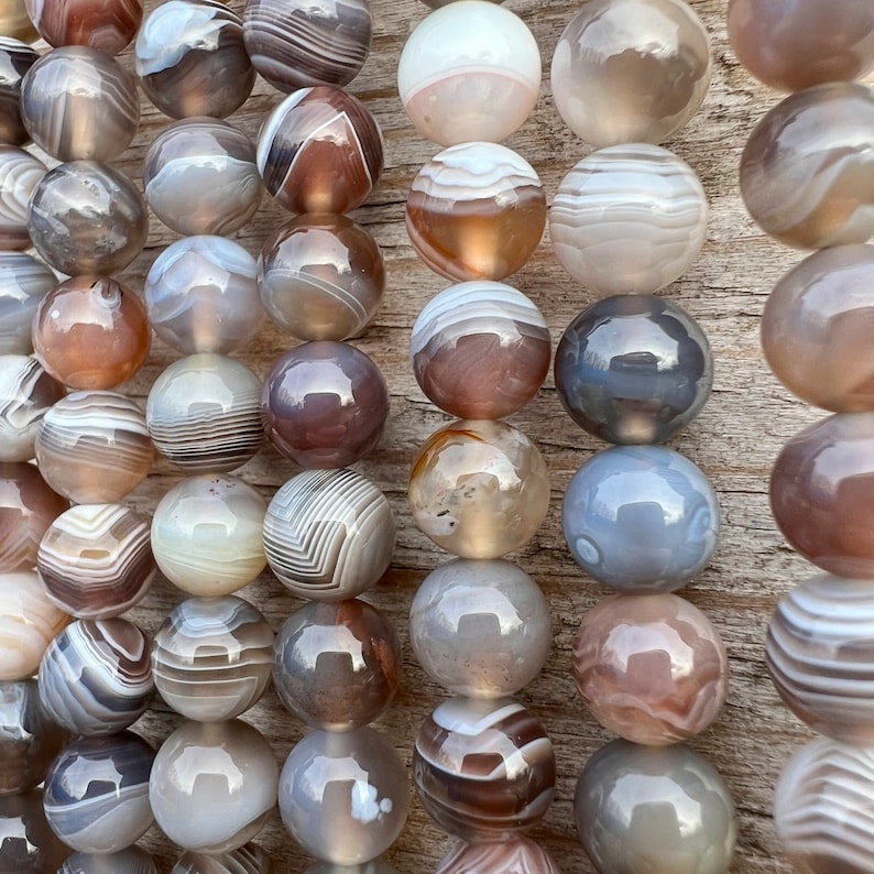 Botswana Agate beads strands lain on a bright wood board in outdoors under natural daylight.