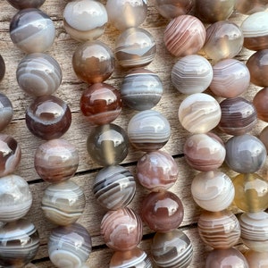 Botswana Agate beads strands lain on a bright wood board in outdoors under natural daylight.