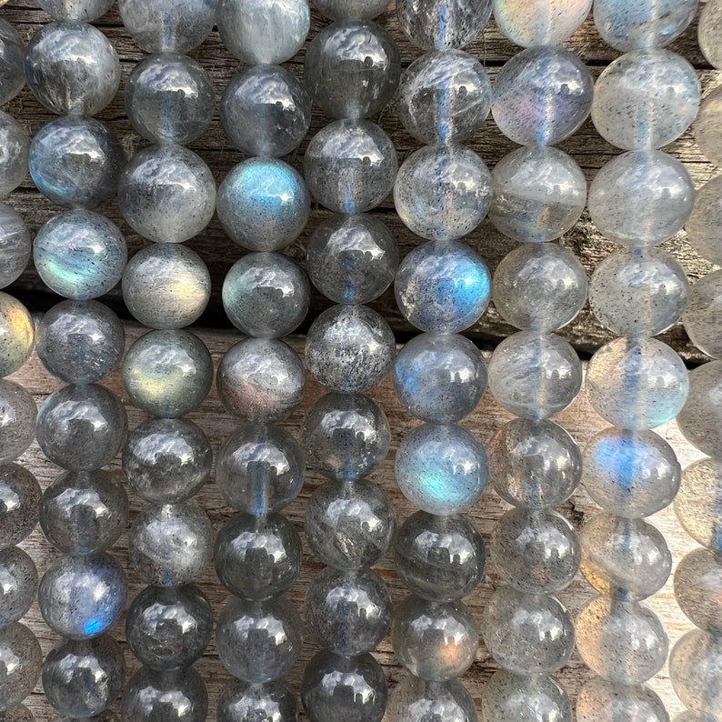 Labradorite stone beads strands laid on a bright wood board in outdoors under natural light. pictured from a close look