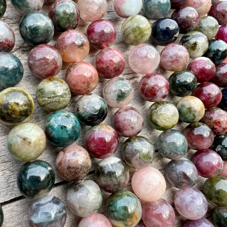 Tourmaline stone beads strands hanging over a bright wood board at outdoors and pictured under natural day light