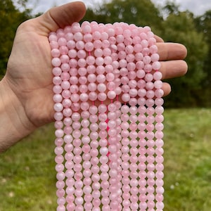 Madagascar rose quartz beads strands held in hand in outdoor