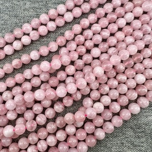 Madagascar rose quartz beads strands laid on a gray background