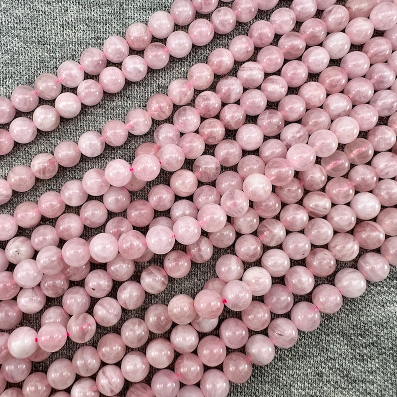 Madagascar rose quartz beads strands laid on a gray background