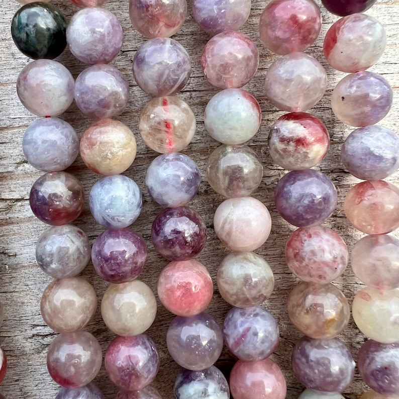 Cherry Tourmaline gemstone beads strands laid on a bright wood board in outdoors under natural daylight.