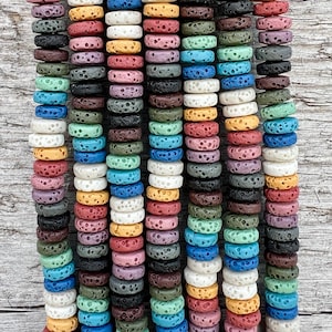 Pode incluir: Uma variedade de contas de rocha vulcânica em diferentes cores, incluindo branco, amarelo, vermelho, laranja, verde, azul, roxo e preto. As contas são todas redondas e têm uma superfície áspera e texturizada.