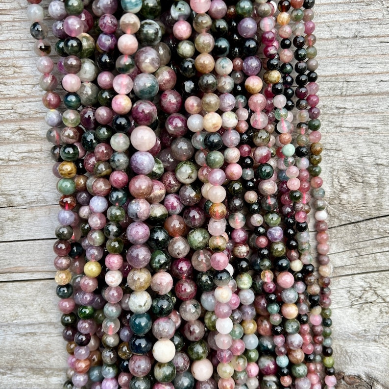 Tourmaline stone beads strands hanging over a bright wood board at outdoors and pictured under natural day light