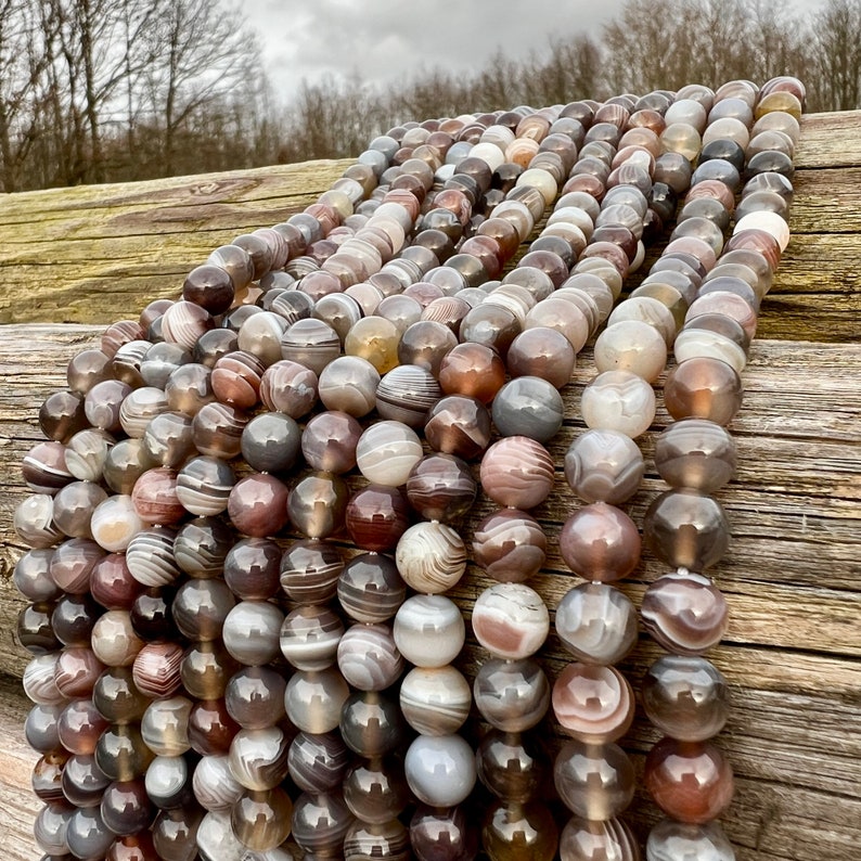 Botswana Agate beads strands lain on a bright wood board in outdoors under natural daylight.