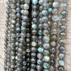 Labradorite stone beads strands laid on a bright wood board in outdoors under natural light.