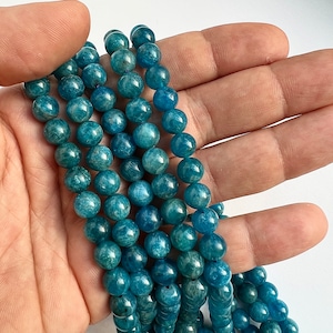 8mm Apatite stone beads strands held in hand on white background