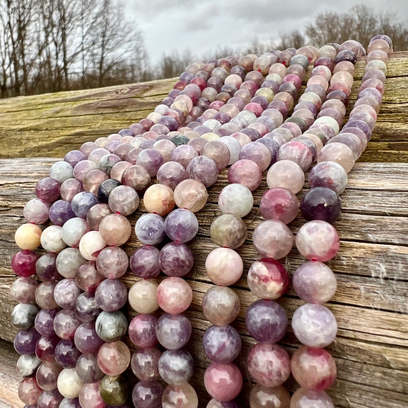 Cherry Tourmaline gemstone beads strands laid on a bright wood board in outdoors under natural daylight.