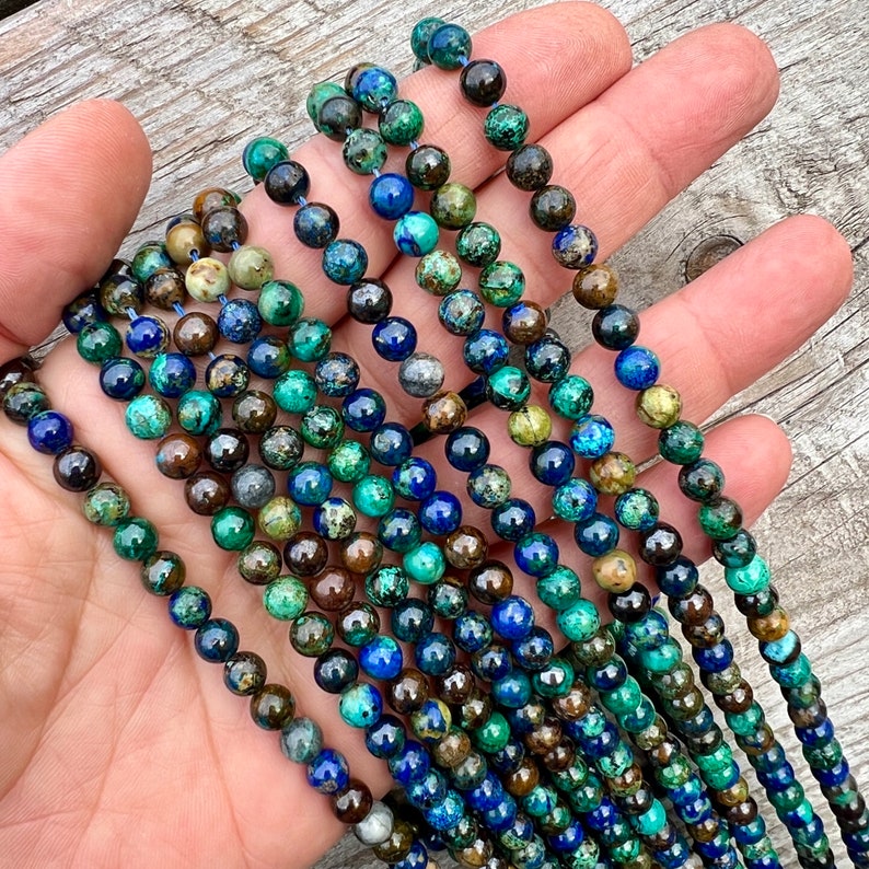 Azurite stone 6mm beads strands held in hand on bright wood surface in outdoor and pictured under natural day light.