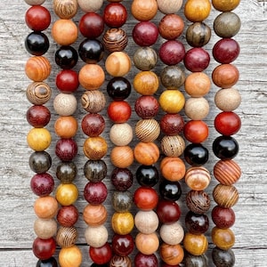 Op de afbeelding: Een streng houten kralen in verschillende tinten bruin, rood en zwart. De kralen hebben een natuurlijk houtnerfpatroon en zijn aan elkaar geregen op een doorzichtig koord.