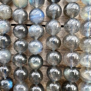 Labradorite stone beads strands laid on a bright wood board in outdoors under natural light. pictured from a close look