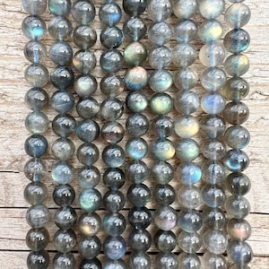 Labradorite stone beads strands laid on a bright wood board in outdoors under natural light.