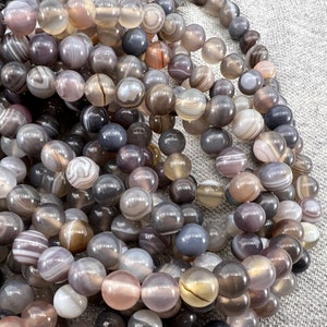 Botswana agate stone beads strands laid on a gray background