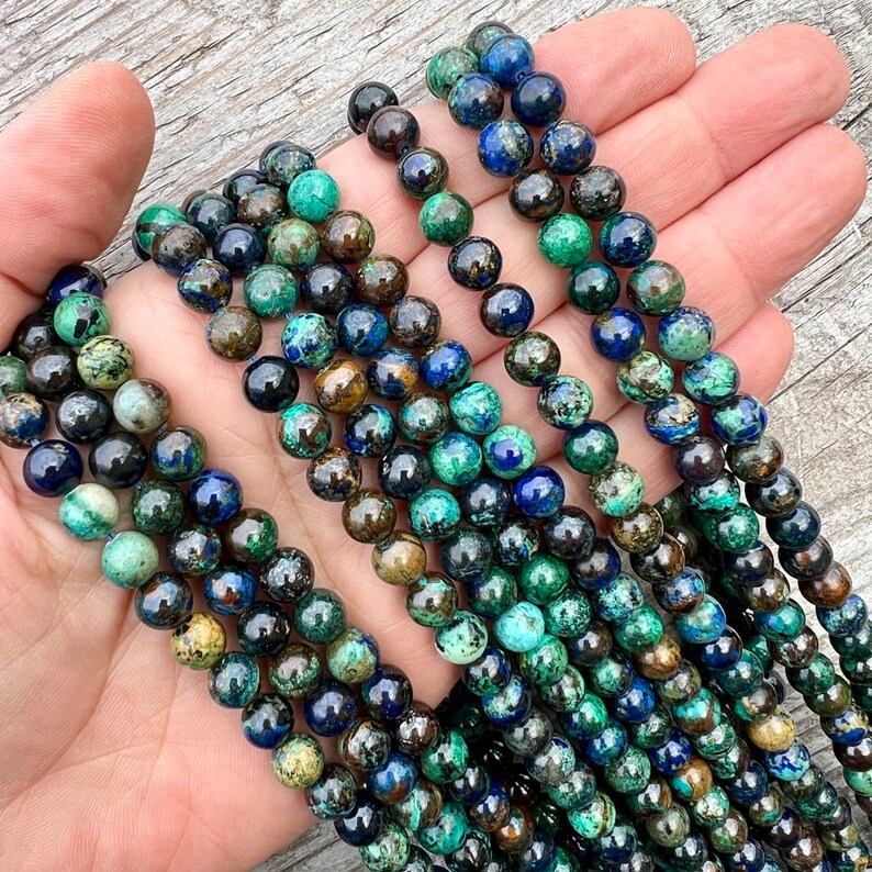 Azurite stone 8mm beads strands held in hand on bright wood surface in outdoor and pictured under natural day light.