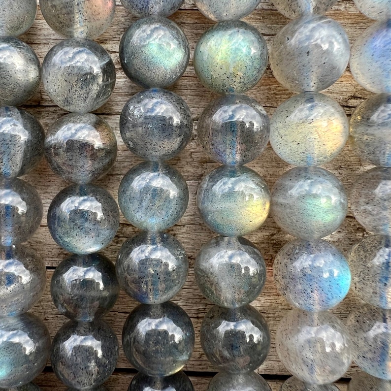 Labradorite stone beads strands laid on a bright wood board in outdoors under natural light. pictured from a close look