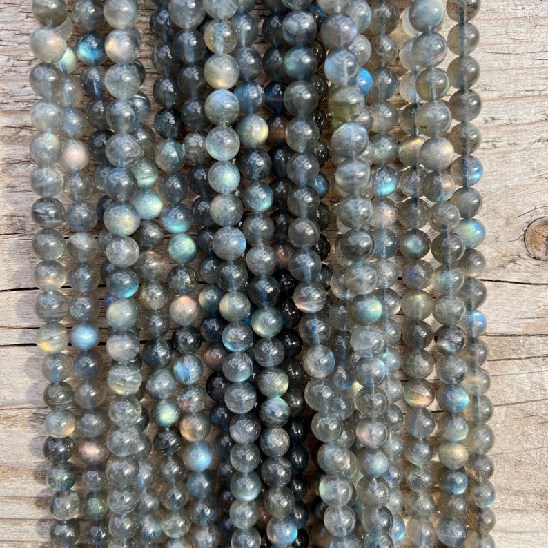 Labradorite stone beads strands laid on a bright wood board in outdoors under natural light.