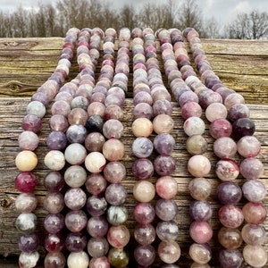 Cherry Tourmaline gemstone beads strands laid on a bright wood board in outdoors under natural daylight.