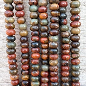 Può includere: Una collana di perle di diaspro rosso, marrone e verde. Le perle sono rotonde e hanno una finitura lucida.