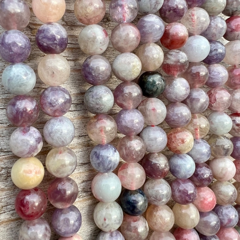 Cherry Tourmaline gemstone beads strands laid on a bright wood board in outdoors under natural daylight.