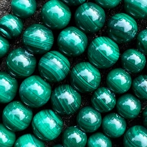 Peut inclure: Gros plan sur un collier de perles rondes en malachite verte. Les perles ont une finition lisse et polie et un motif tourbillonnant.