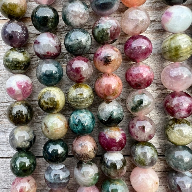 Tourmaline stone beads strands hanging over a bright wood board at outdoors and pictured under natural day light