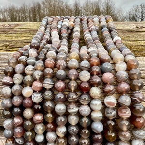 Botswana Agate beads strands lain on a bright wood board in outdoors under natural daylight.