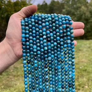 Apatite stone beads strands held in hand in outdoor under natural light