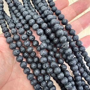 8mm lava beads strands held in hand on a bright wood board