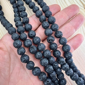 10mm lava beads strands held in hand on a bright wood board
