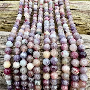 Cherry Tourmaline gemstone beads strands laid on a bright wood board in outdoors under natural daylight.