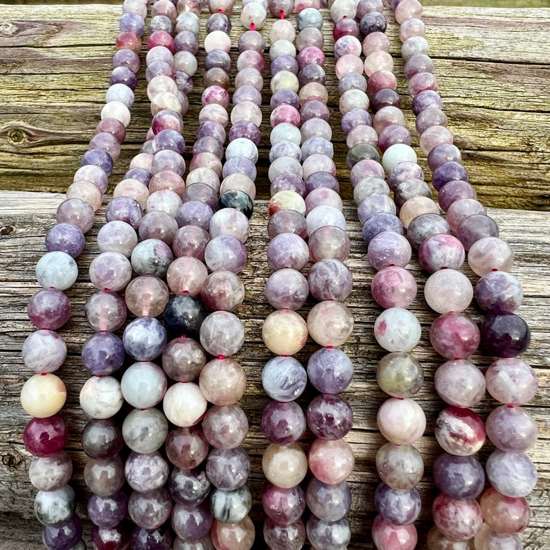 Cherry Tourmaline gemstone beads strands laid on a bright wood board in outdoors under natural daylight.