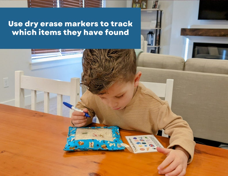 May include: A blue fabric pouch with a clear window containing small objects, accompanied by a card with colorful icons and the text 'Use dry erase markers to track which items they have found' printed on the image overlay.