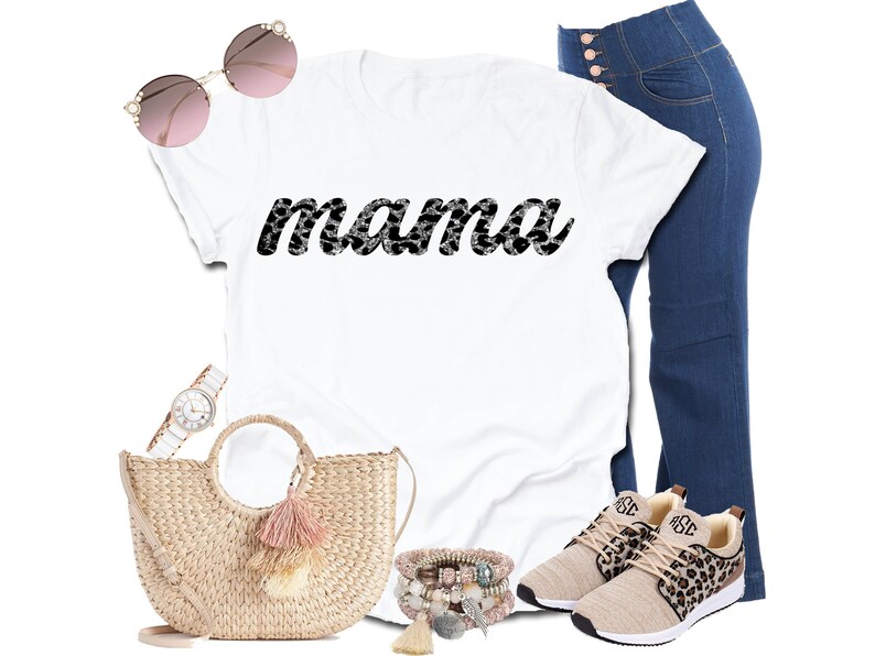 以下が含まれることがあります： 白のTシャツに「mama」の文字が白黒のヒョウ柄でプリントされています。画像には、ハイウエストのブルージーンズ、ヒョウ柄のアクセントが付いたベージュのスニーカー、麦わらハンドバッグ、サングラス、腕時計、ブレスレットも含まれています。