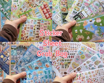 May include: A collection of colorful sticker sheets featuring various designs, including animals, food, and other cute illustrations. The text "Sticker Sheet Grab Bag" is visible. The stickers are held in hands, showcasing the variety of styles.