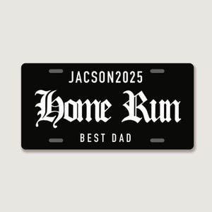Puede incluir: Una placa de matr&iacute;cula rectangular negra con texto en blanco. La l&iacute;nea superior dice JACSON2025 en una fuente sans-serif. El centro presenta las palabras Home Run en una letra g&oacute;tica decorativa grande. La l&iacute;nea inferior dice BEST DAD.