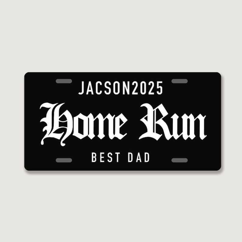 Puede incluir: Una placa de matr&iacute;cula rectangular negra con texto en blanco. La l&iacute;nea superior dice JACSON2025 en una fuente sans-serif. El centro presenta las palabras Home Run en una letra g&oacute;tica decorativa grande. La l&iacute;nea inferior dice BEST DAD.