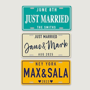 Puede incluir: Tres placas de matr&iacute;cula rectangulares. La superior es verde azulado con texto blanco JUNE 8TH, JUST MARRIED, THE SMITHS. La central es crema con texto negro JUST MARRIED, Jane & Mark, AUG 2025. La inferior es amarilla con texto azul NEY YORK, MAX & SALA y dos corazones con 2023.