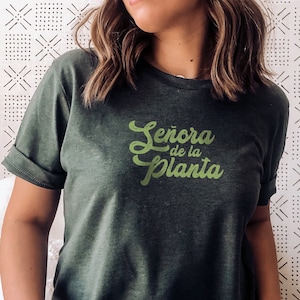 Op de afbeelding: Een donkergroen T-shirt met de tekst "Senora de la Planta" in een groen retro-lettertype.