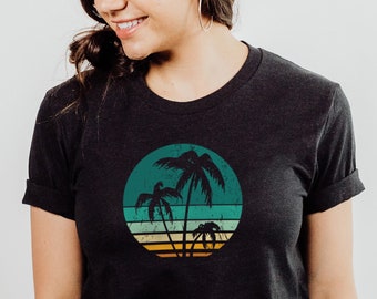 May include: A black t-shirt featuring a retro-style graphic of palm trees in a circle with a sunset background.
