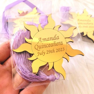 May include: Gold mirror sun with a purple tassel, featuring the text "Amanda Quinceañera July 29th 2023".
