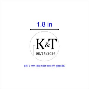 May include: A white circular design with the letters "K&T" and the date "08/15/2026" in black. The text "1.8 in" is above the circle, and "Slit: 3 mm (fits most thin-rim glasses)" is below. The design is on a white background.