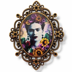 Peut inclure: Un cadre décoratif ovale de couleur bronze représentant un portrait de Frida Kahlo. Le portrait est entouré de fleurs et de feuillages colorés. Le cadre présente un design orné avec des accents en forme d'étoile.